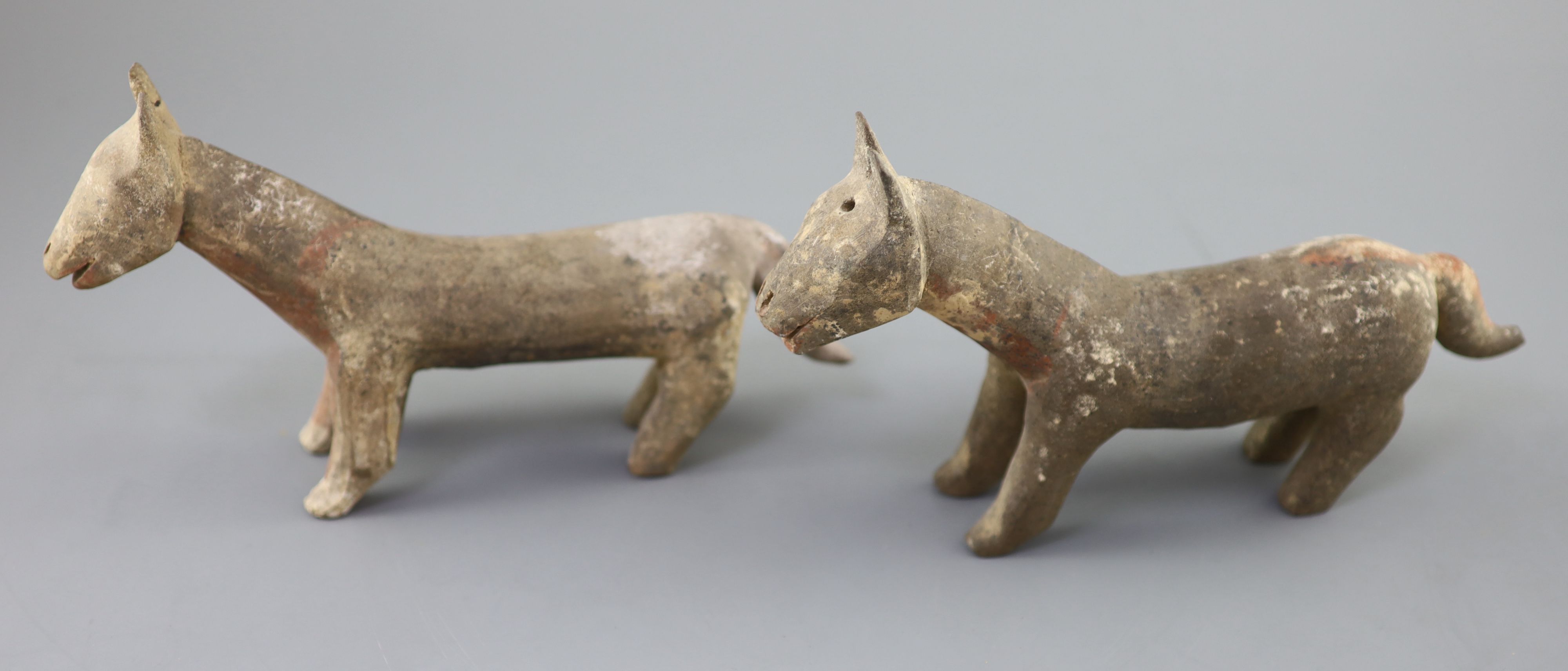 A pair of Chinese grey pottery models of dogs, Han dynasty or later, 26cm long, repairs